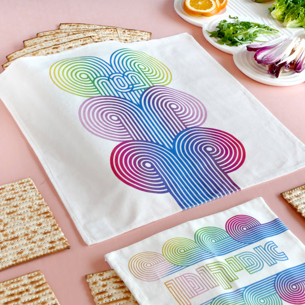 set of a Matzah cover and Afikoman bag, crafted from fine off-white cotton velvet. The design features an op-art-inspired wave pattern in stunning multicolor Ombre tones, printed using state-of-the-art 'Kornit Digital' textile printers.