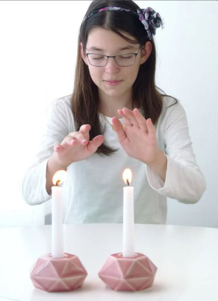 Person interacting with two pink lit candles on geometric candle holders.