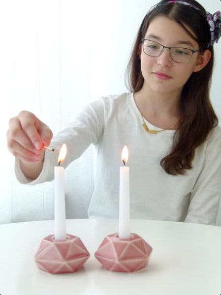 Person pink lighting candles on a white surface