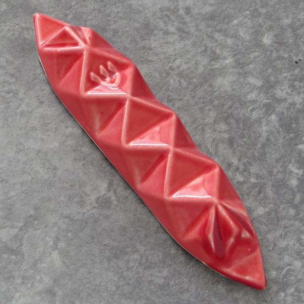 A modern Mezuzah case inspired by Origami, a piece of contemporary geometric Judaica. made of clay with red glaze