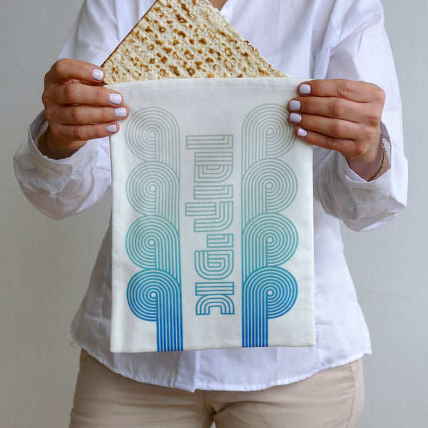 Person holding a piece of bread over a towel with 'INDIE' printed on it.