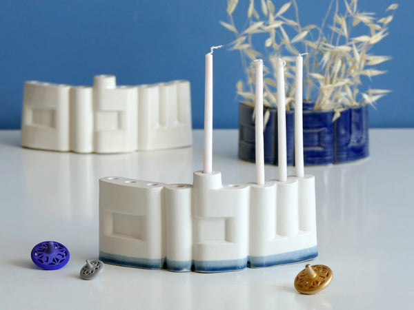 **Innovative “Shalom” Hanukkah Menorah (Chanukiah)**
A unique arc-shaped menorah spelling the Hebrew word *Shalom* (שלום), slip-cast by us in our Tel Aviv studio. Off-white clay, matte off-white glaze, with a subtle blue accent along the base—blending tradition with a fresh, modern look.