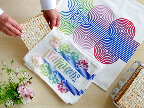 stylish and trendy set of a Matzah cover and Afikoman bag, crafted from fine off-white cotton. The design features an op-art-inspired wave pattern in stunning multicolor Ombre tones, printed using state-of-the-art 'Kornit Digital' textile printers. This design draws inspiration from the story of Exodus, merging tradition with contemporary aesthetic.