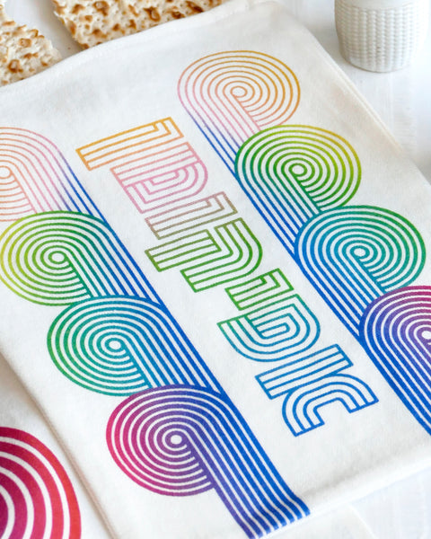 stylish and trendy set of a Matzah cover and Afikoman bag, crafted from fine off-white cotton. The design features an op-art-inspired wave pattern in stunning multicolor Ombre tones, printed using state-of-the-art 'Kornit Digital' textile printers. This design draws inspiration from the story of Exodus, merging tradition with contemporary aesthetic.