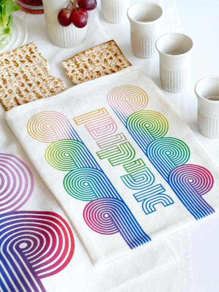 stylish and trendy set of a Matzah cover and Afikoman bag, crafted from fine off-white cotton. The design features an op-art-inspired wave pattern in stunning multicolor Ombre tones, printed using state-of-the-art 'Kornit Digital' textile printers. This design draws inspiration from the story of Exodus, merging tradition with contemporary aesthetic.