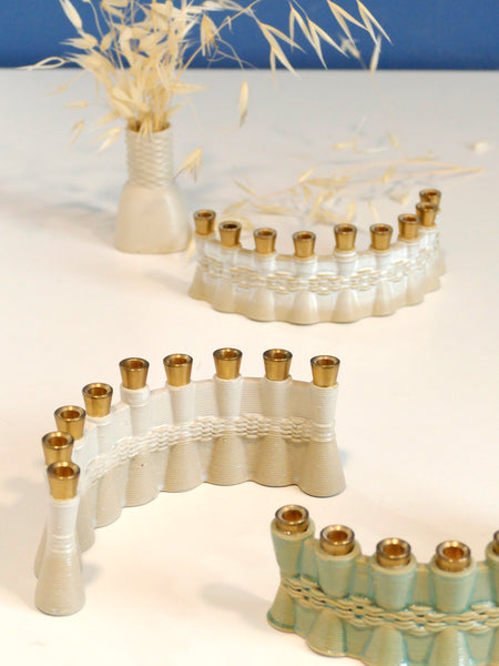 This contemporary Hanukkah Menorah features an arc shape with a delicate weaving pattern, created using a unique method with a clay 3D printer. Its gentle details and modest proportions make it look like a modern jewel.