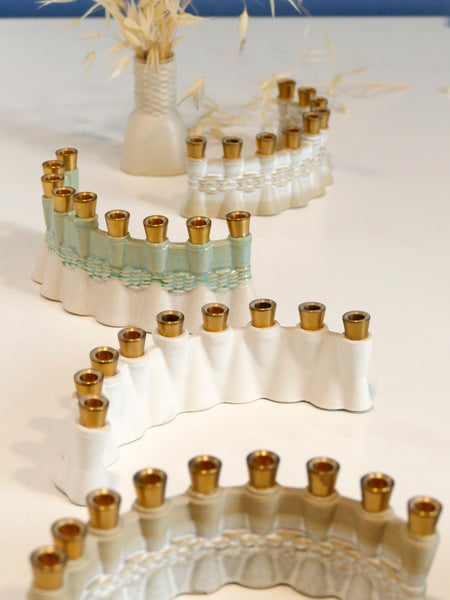 This contemporary Hanukkah Menorah features an arc shape with a delicate weaving pattern, created using a unique method with a clay 3D printer. Its gentle details and modest proportions make it look like a modern jewel.